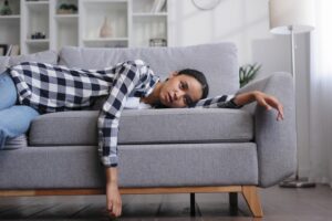 Woman laying on couch feeling tired.