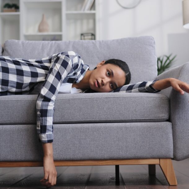 Woman laying on couch feeling tired.