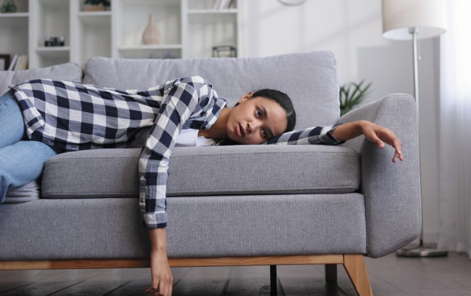 Woman laying on couch feeling tired.