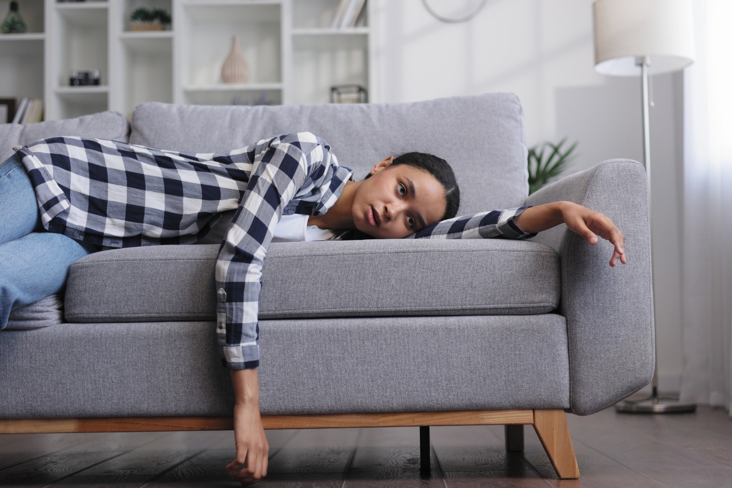 Woman laying on couch feeling tired.