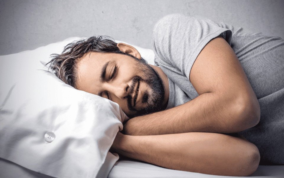 Man looking comfy in bed after learning how to get more sleep.