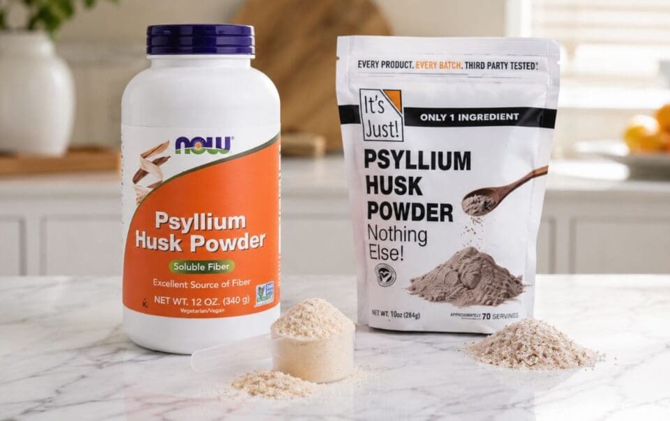 Two containers of psyllium husk powder, ideal for psyllium husk weight loss support, sit on a marble counter. One is a large NOW bottle and the other an It's Just! pouch, each with scoops of powder in front and fruits blurred in the background.